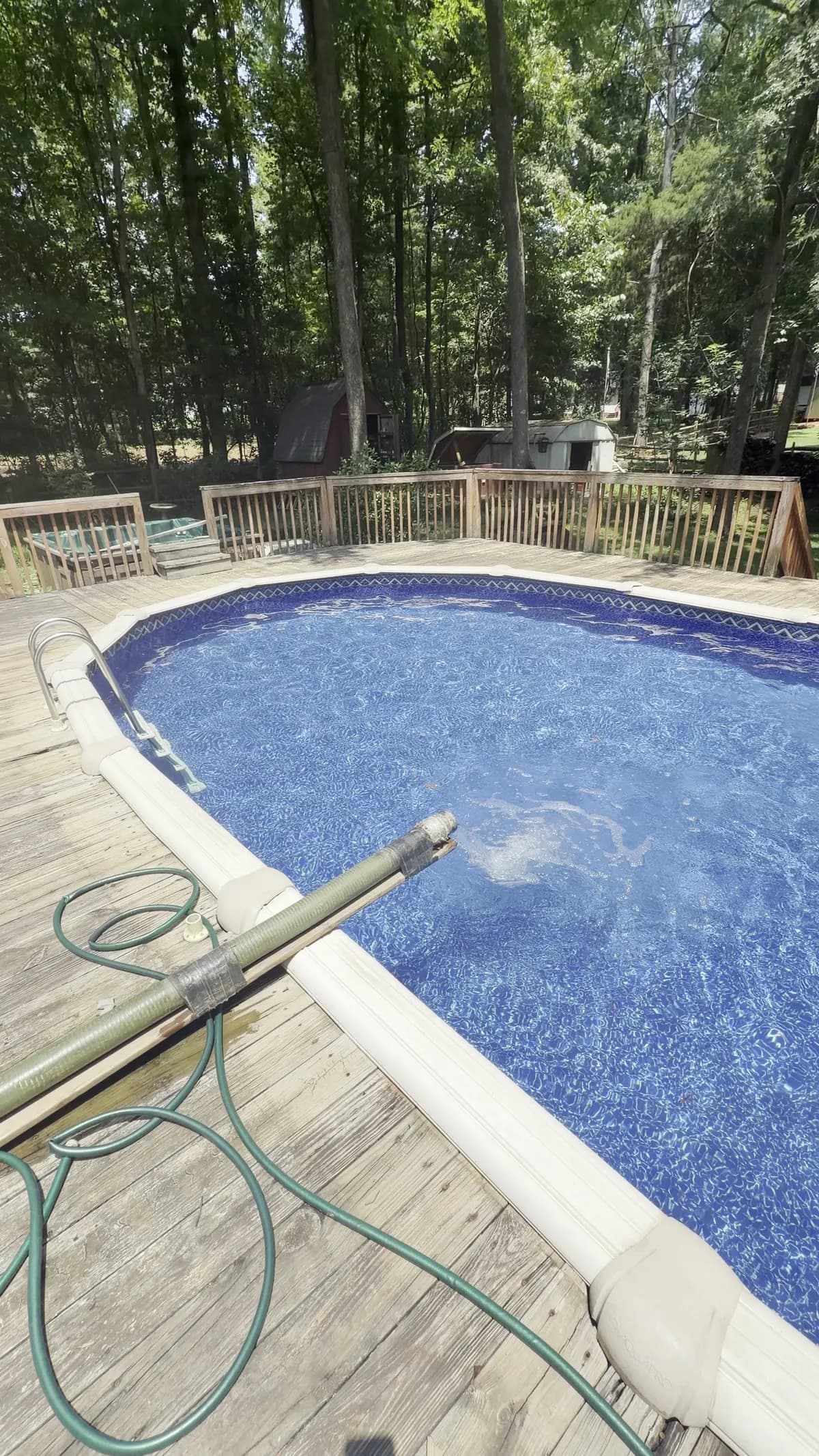 Above-ground pool on a wooden deck being vacuumed